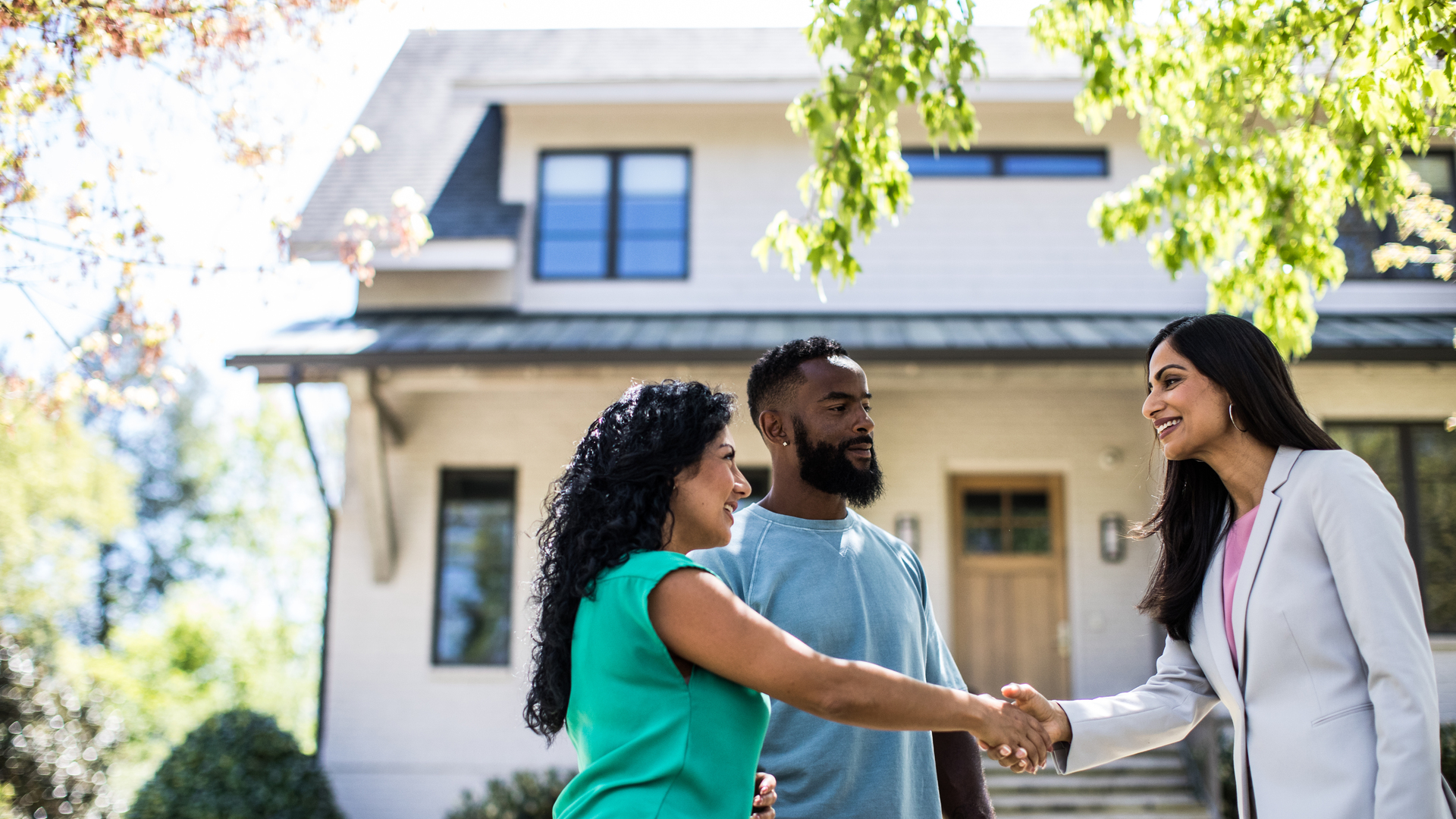 Couple meeting with real estate agent in front of home