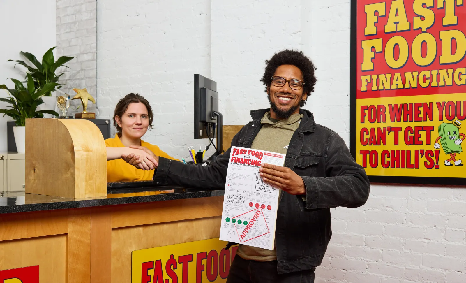 A Chili's worker behind the counter shaking the hand of a customer participating in the chain's "Fast Food Financing" campaign.