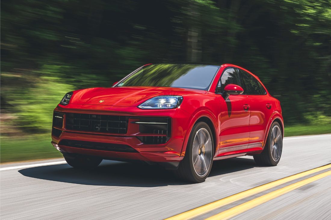Front view of red Porsche Cayenne E-Hybrid driving down a road.