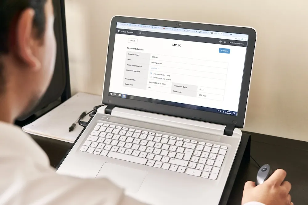 city boiler repair man using virtual terminal on laptop