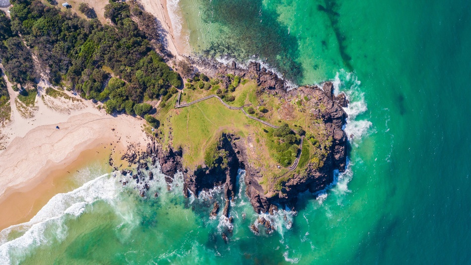 Norries Headland - an aerial shot of waves crashing against the headland which juts out from the beach