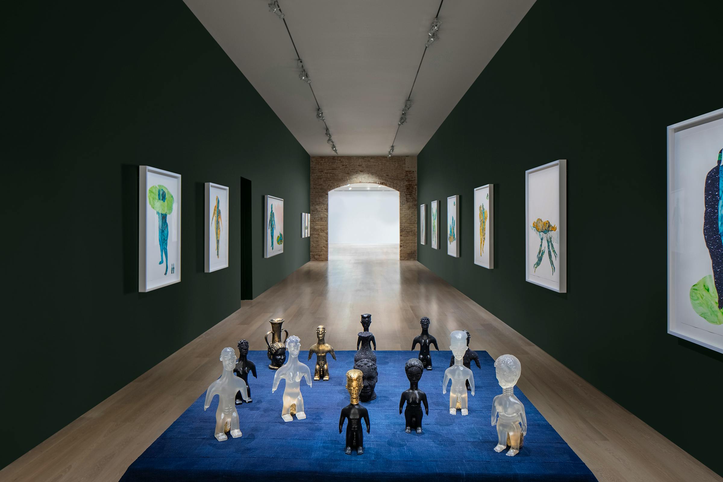 Various collages and sculptures representing women and groups of people displayed in an art gallery.