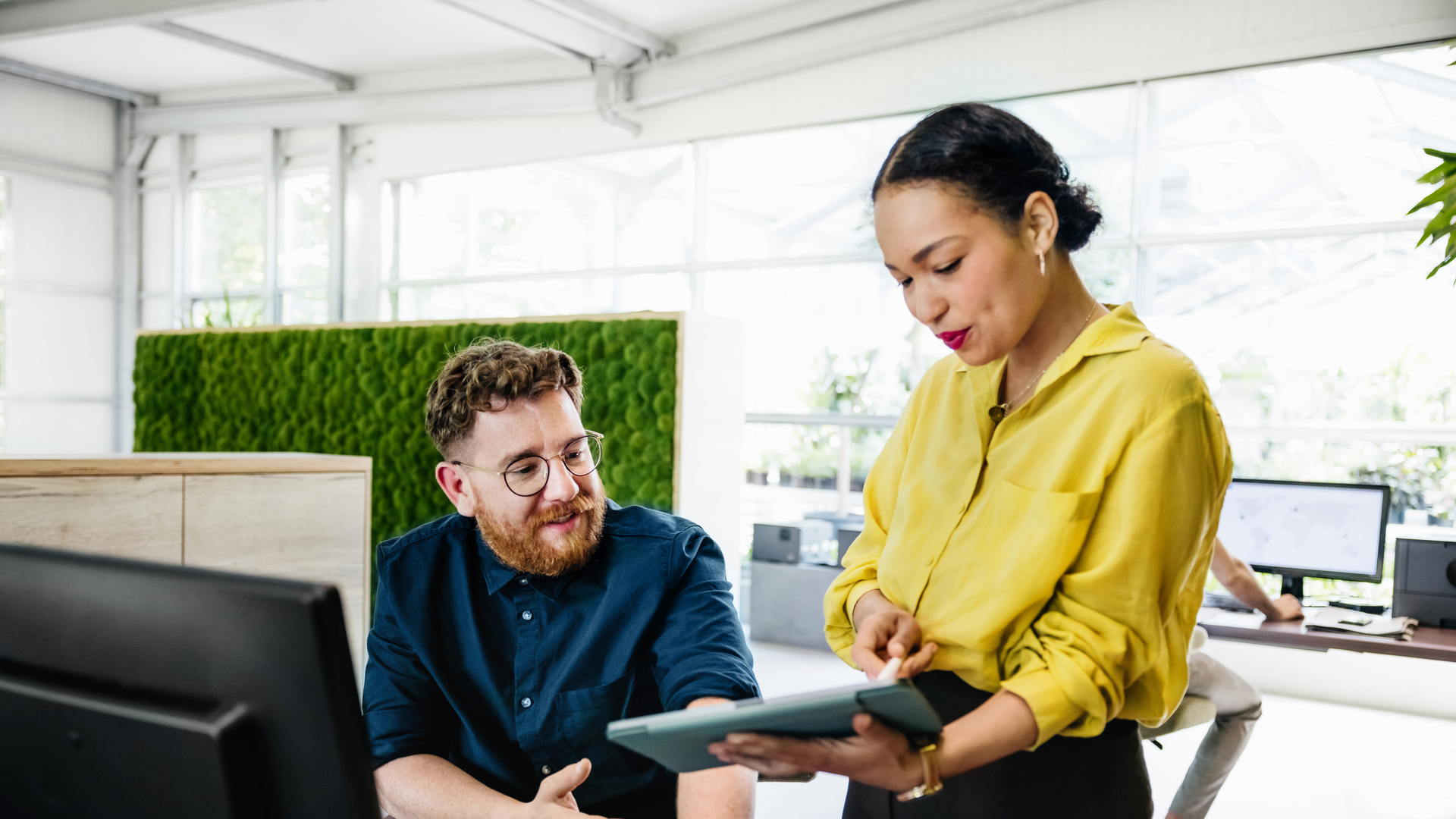 Office Manager Showing Documents On Digital Tablet To Colleague