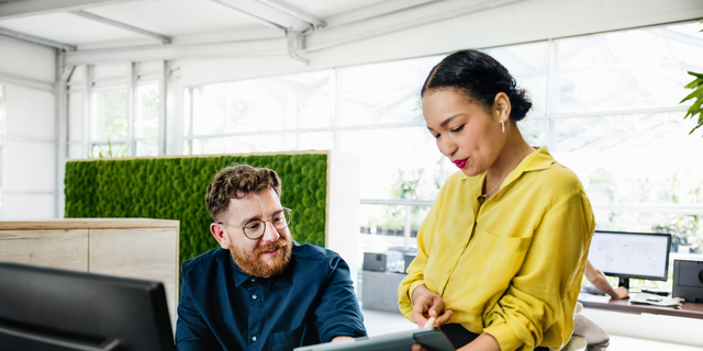 Office Manager Showing Documents On Digital Tablet To Colleague