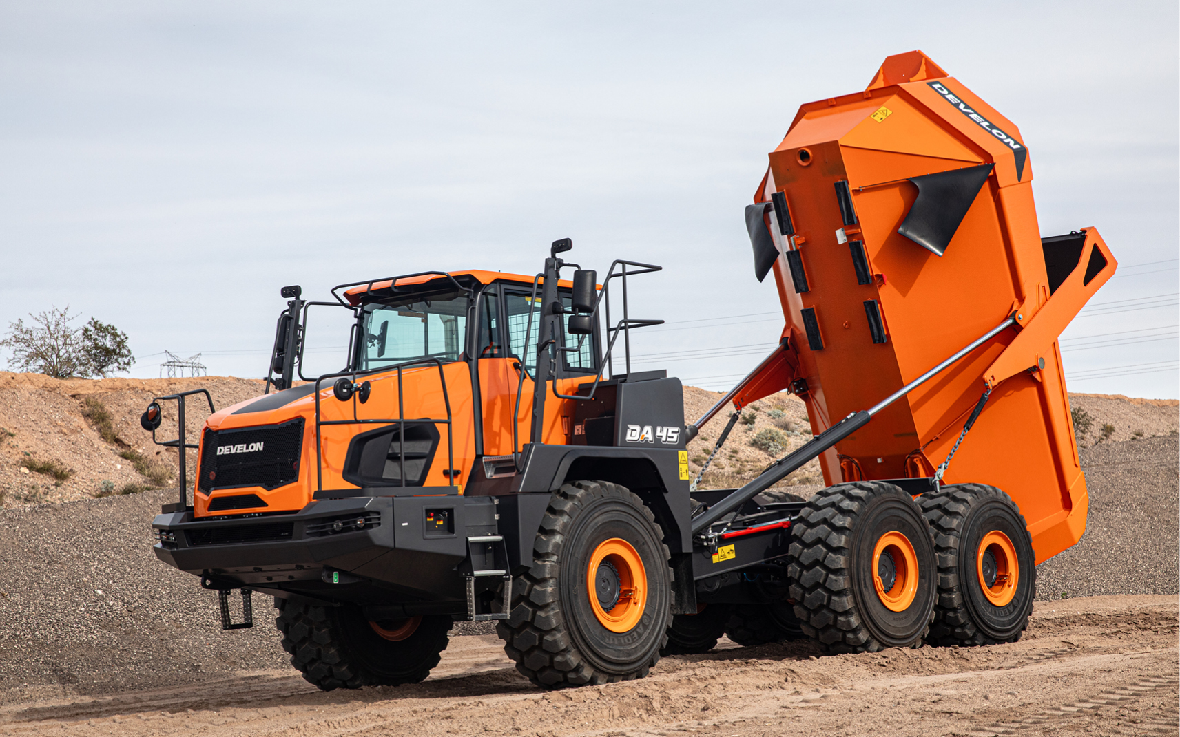 A DEVELON DA45-7 articulated dump truck unloading rocks, ideal for a year-end equipment purchase tax deduction.