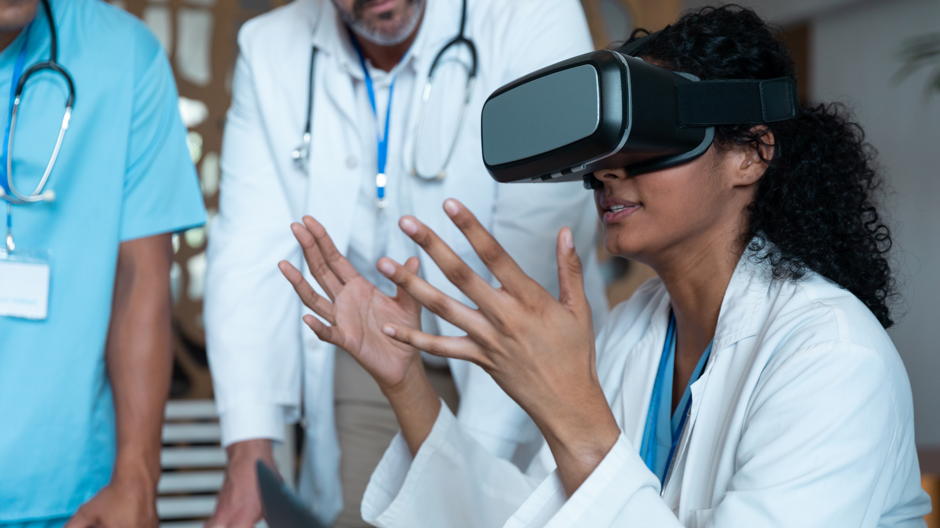 Diverse male and female doctors wearing face masks sitting at table and using vr glasses