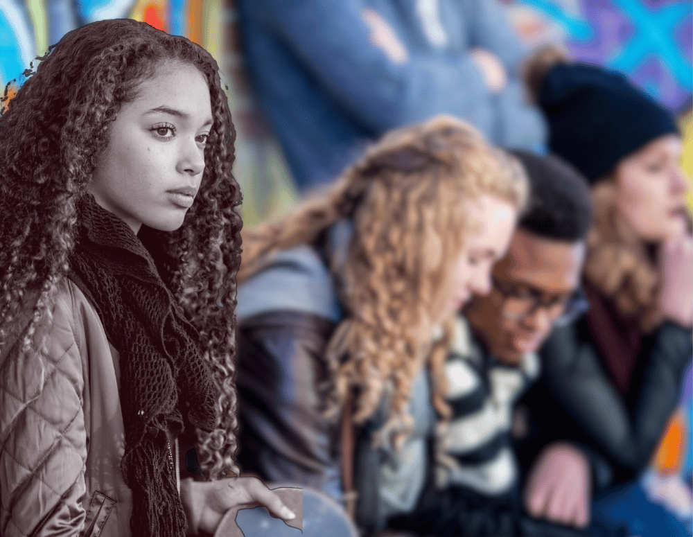 Teen girl looks sad while other teens talk to each other.