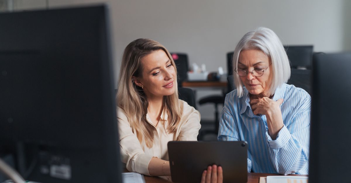 Two adult women sitting together and looking at a tablet