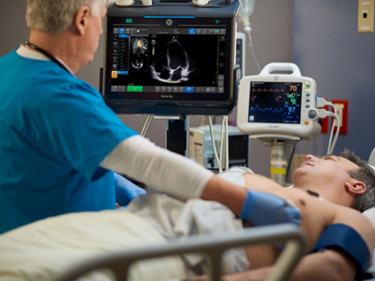 A clinician conducts a cardiac ultrasound exam for a patient in the hospital. Caption Guidance on the Venue™ family of ultrasound systems to perform heart scans guided by AI