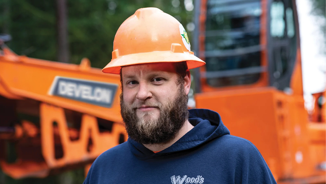 Owner of Hiett Logging standing in front of a DEVELON forestry machine.