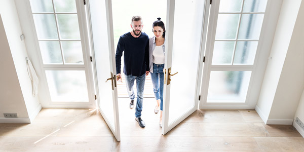 couple walking through french doors into their home