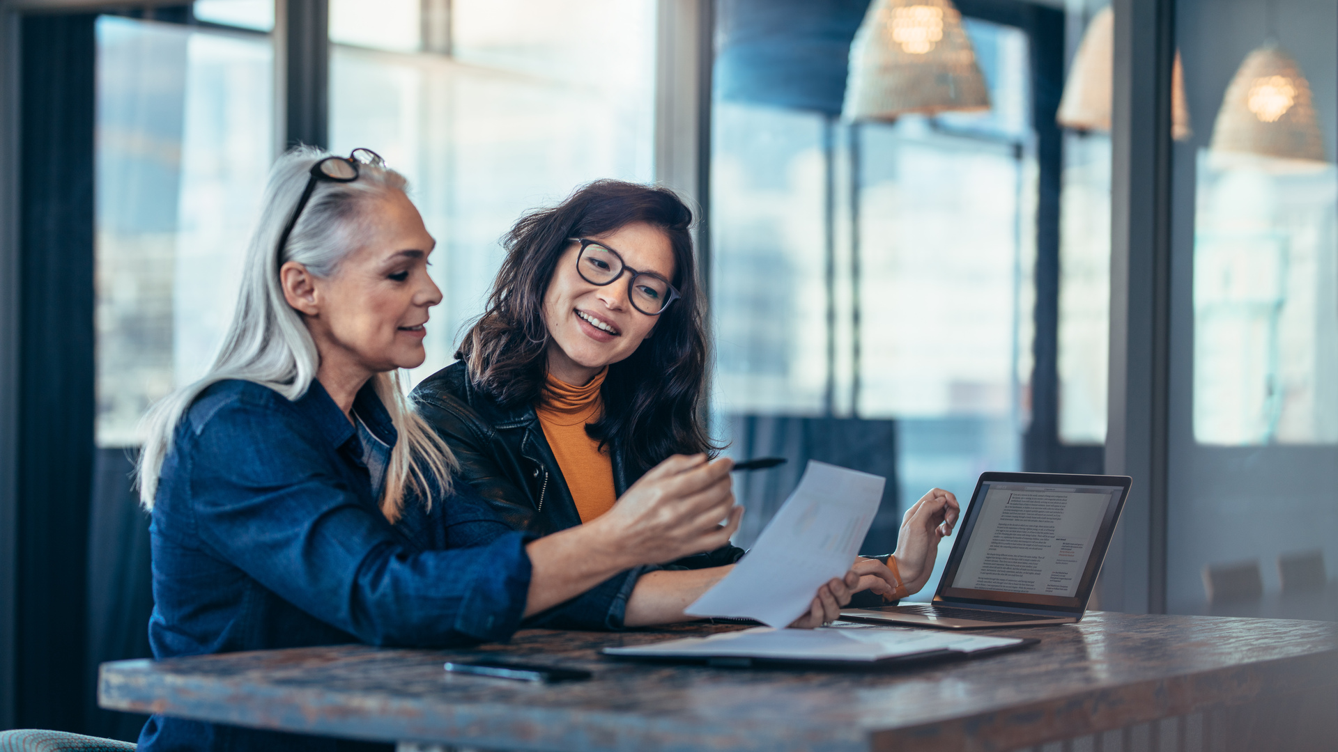 Two women analyzing documents at office