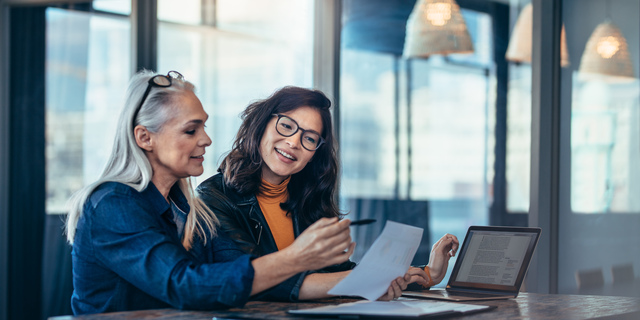 Two women analyzing documents at office