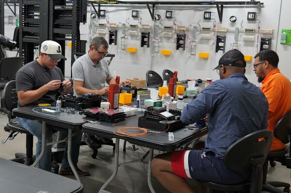 BICSI hands-on installation training course students practicing fiber optic termination and splicing