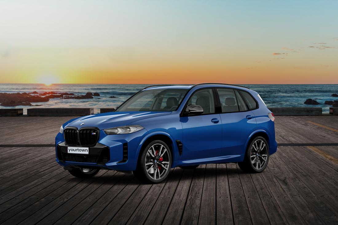 A blue BMW X5 M60i parked on a beachside pier at sunset.