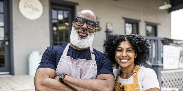 Portrait of father and daughter small business owners in front of family business