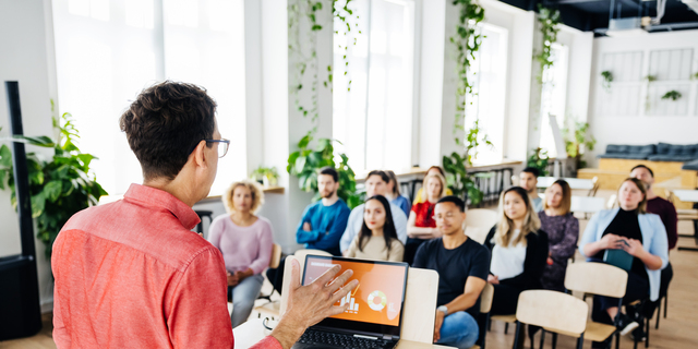 Seminar Host Giving Short Presentation To Small Audience