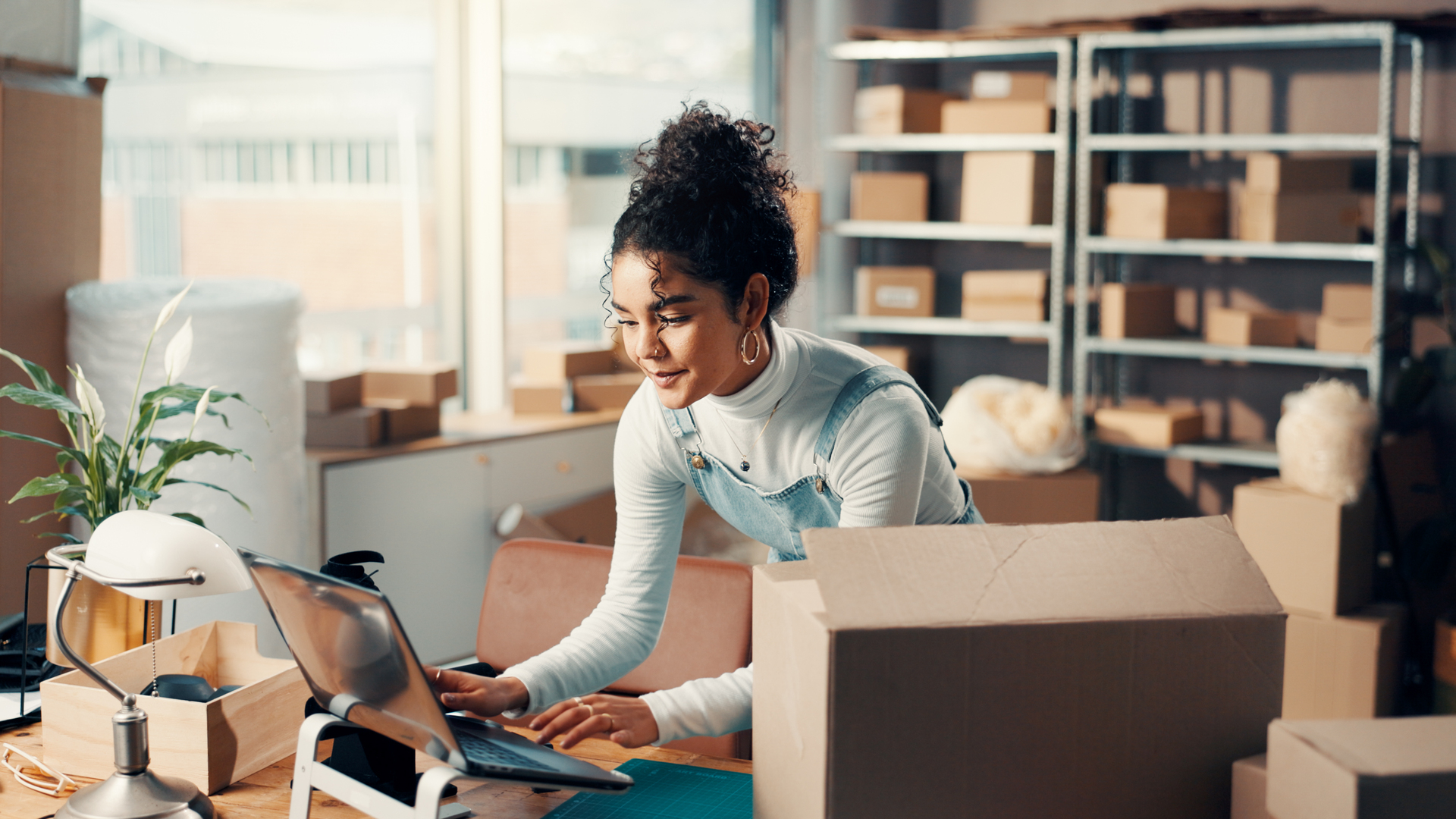 Logistics, laptop and happy woman typing in office for ecommerce, procurement email or distribution. Computer, shipping distributor or online for order update, stock or supply chain in small business