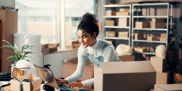 Logistics, laptop and happy woman typing in office for ecommerce, procurement email or distribution. Computer, shipping distributor or online for order update, stock or supply chain in small business