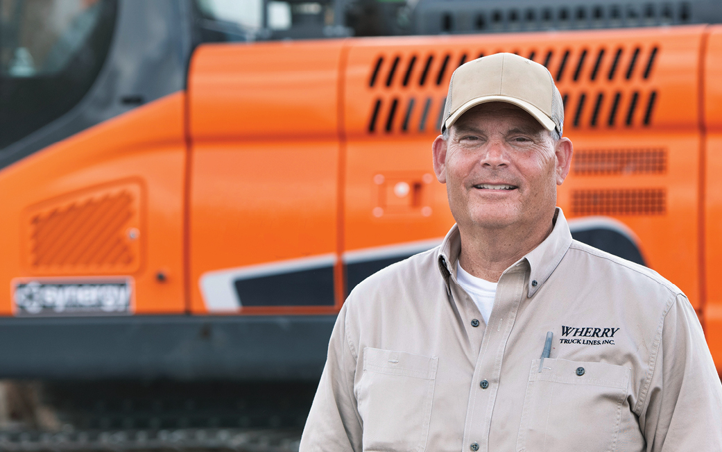 Kendell Wherry of Wherry Truck Lines next to a DEVELON crawler excavator.