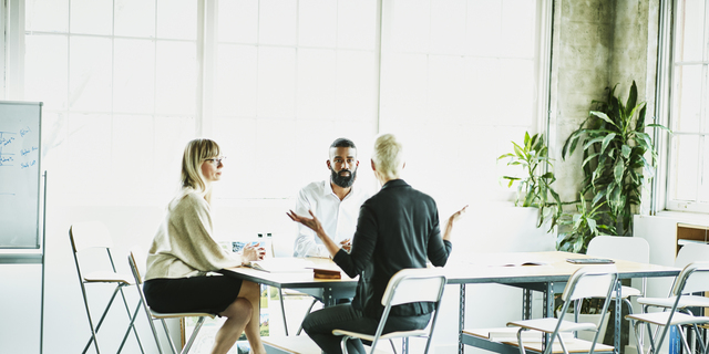 Female business owner leading project meeting with employees in design studio conference room