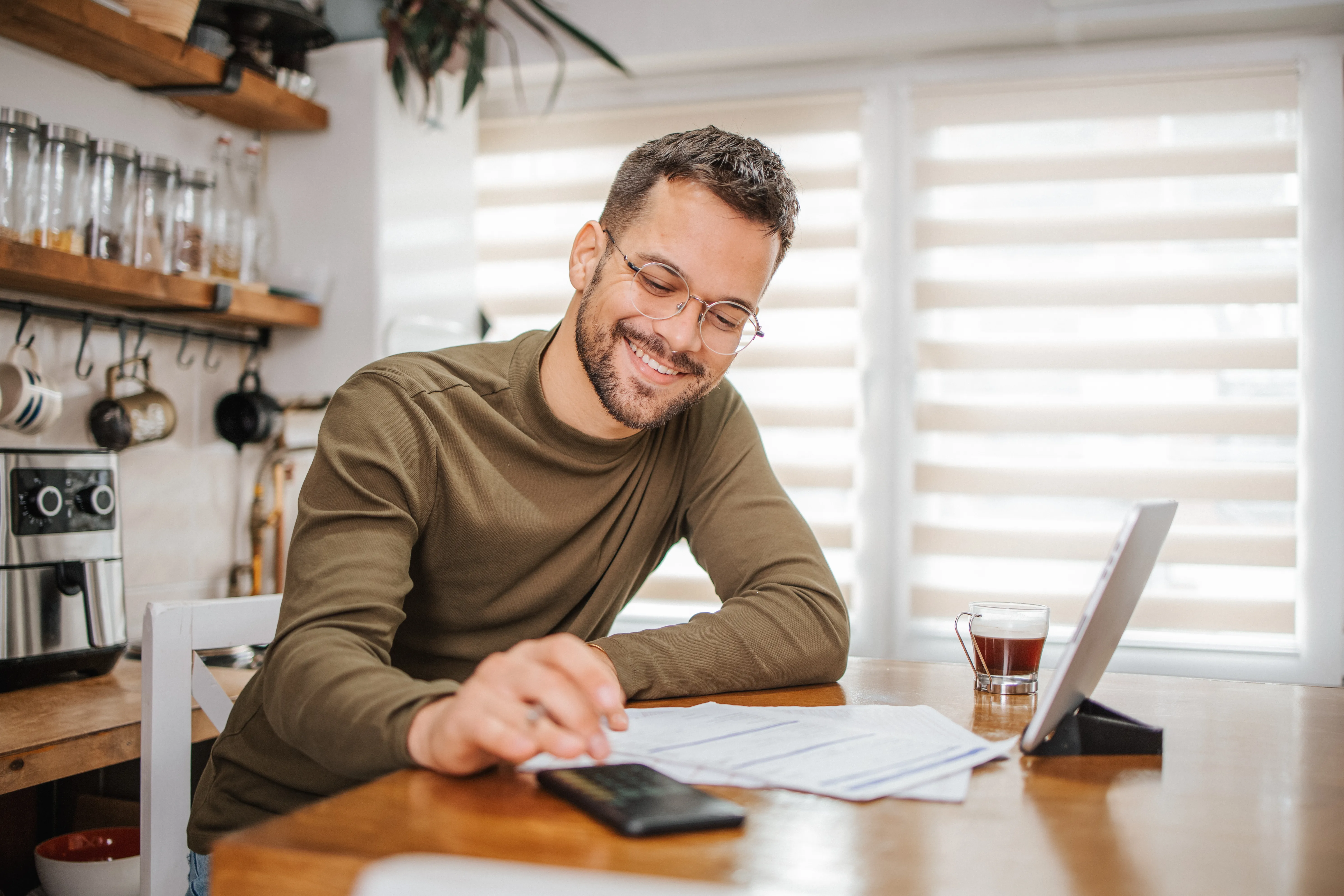 Smiling male at kitchen table going through finances.  