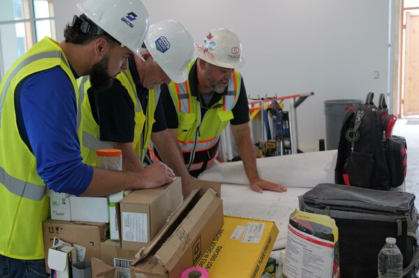 BICSI RCDD certified professionals reviewing telecommunications schematics and blueprints on a construction site