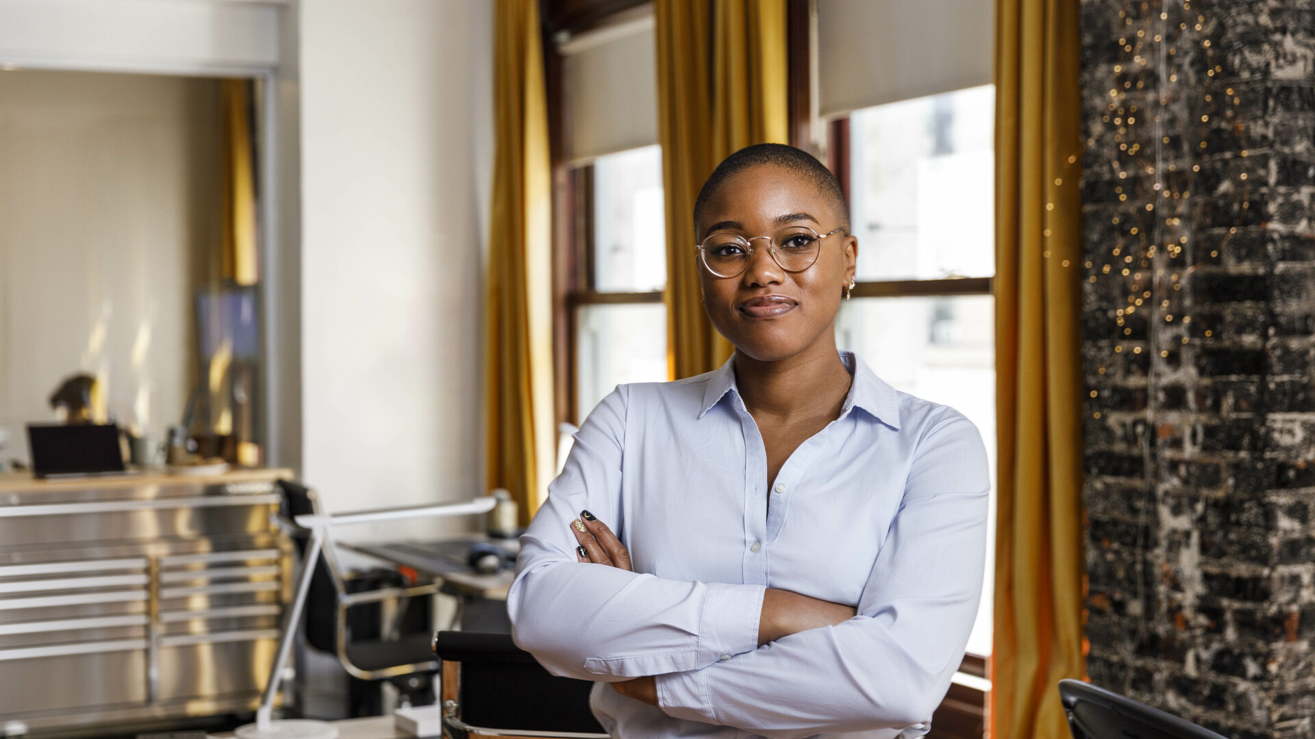 Confident female entrepreneur standing with arms crossed at office