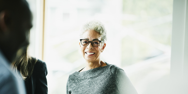 Portrait of smiling senior businesswoman in discussion with coworkers