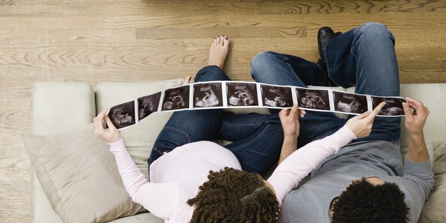 Pregnant African couple looking at ultrasound pictures