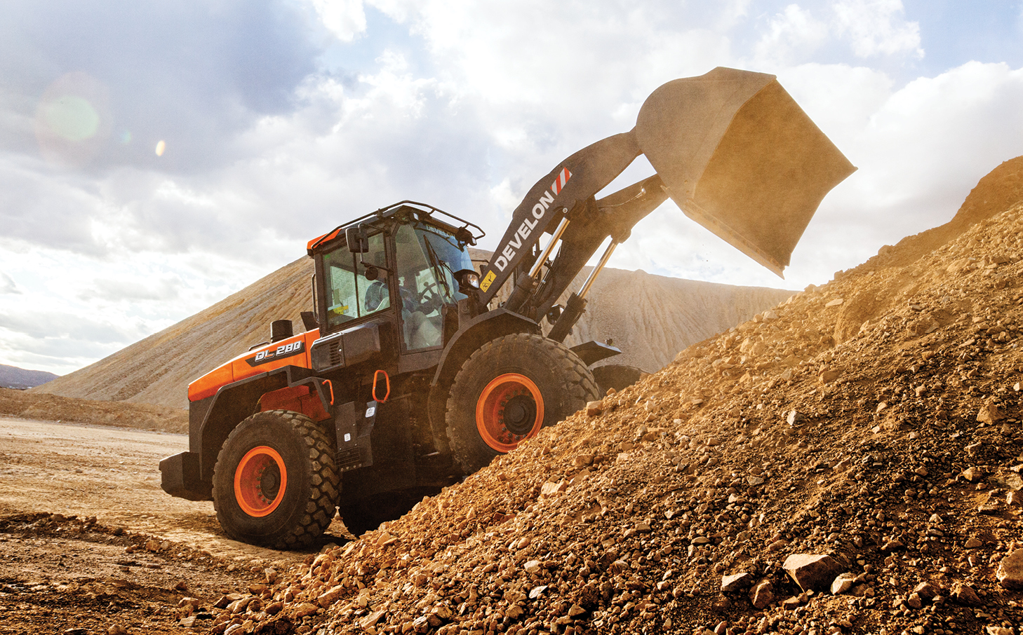 A DEVELON wheel loader at an incline on a large dirt mound.