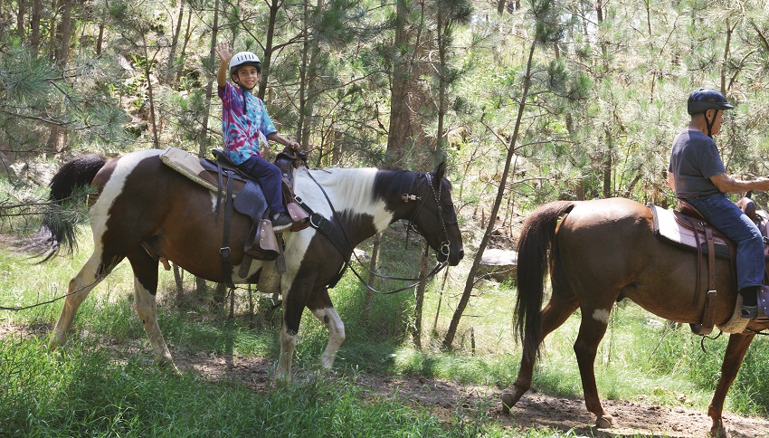 A grandkid waving from a trail ride in South Dakota