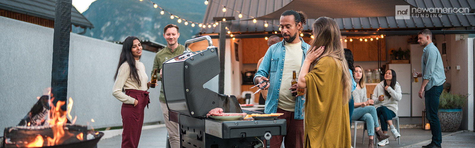 A diverse group of people enjoy a cook-out together in someone's backyard 