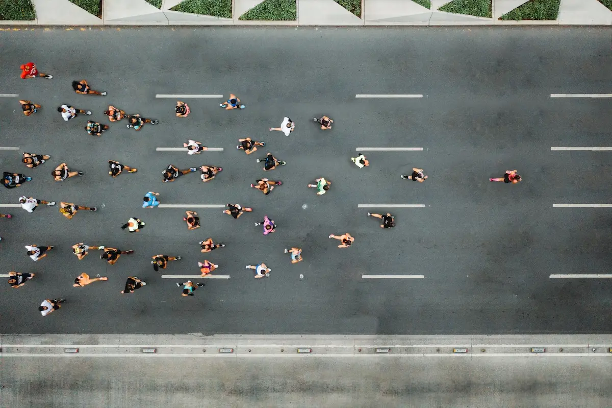 Marathon runners chasing behind the lead runner on a wide street with five lanes