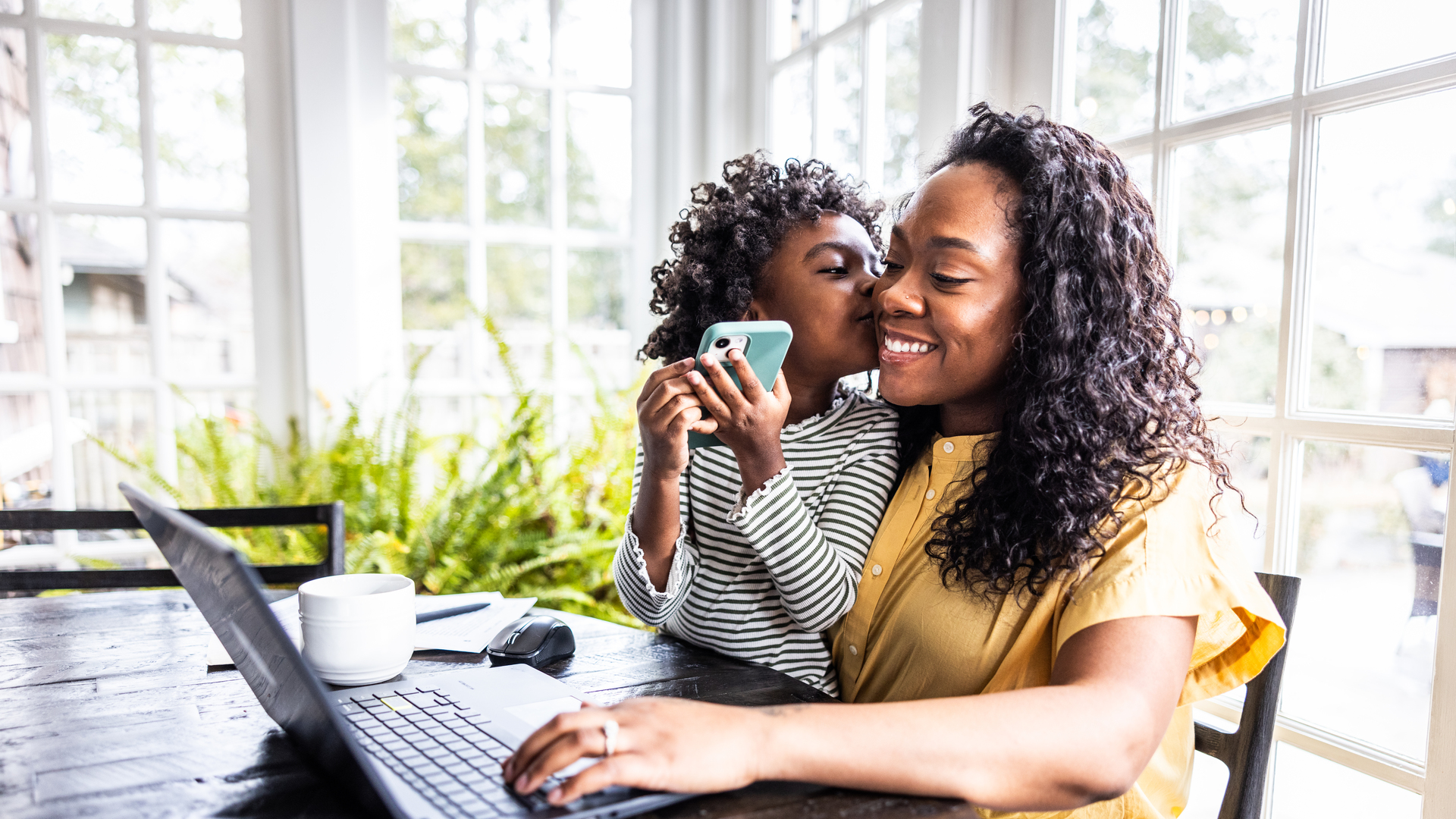 Mother trying to work on laptop while her young daughter is distracting her
