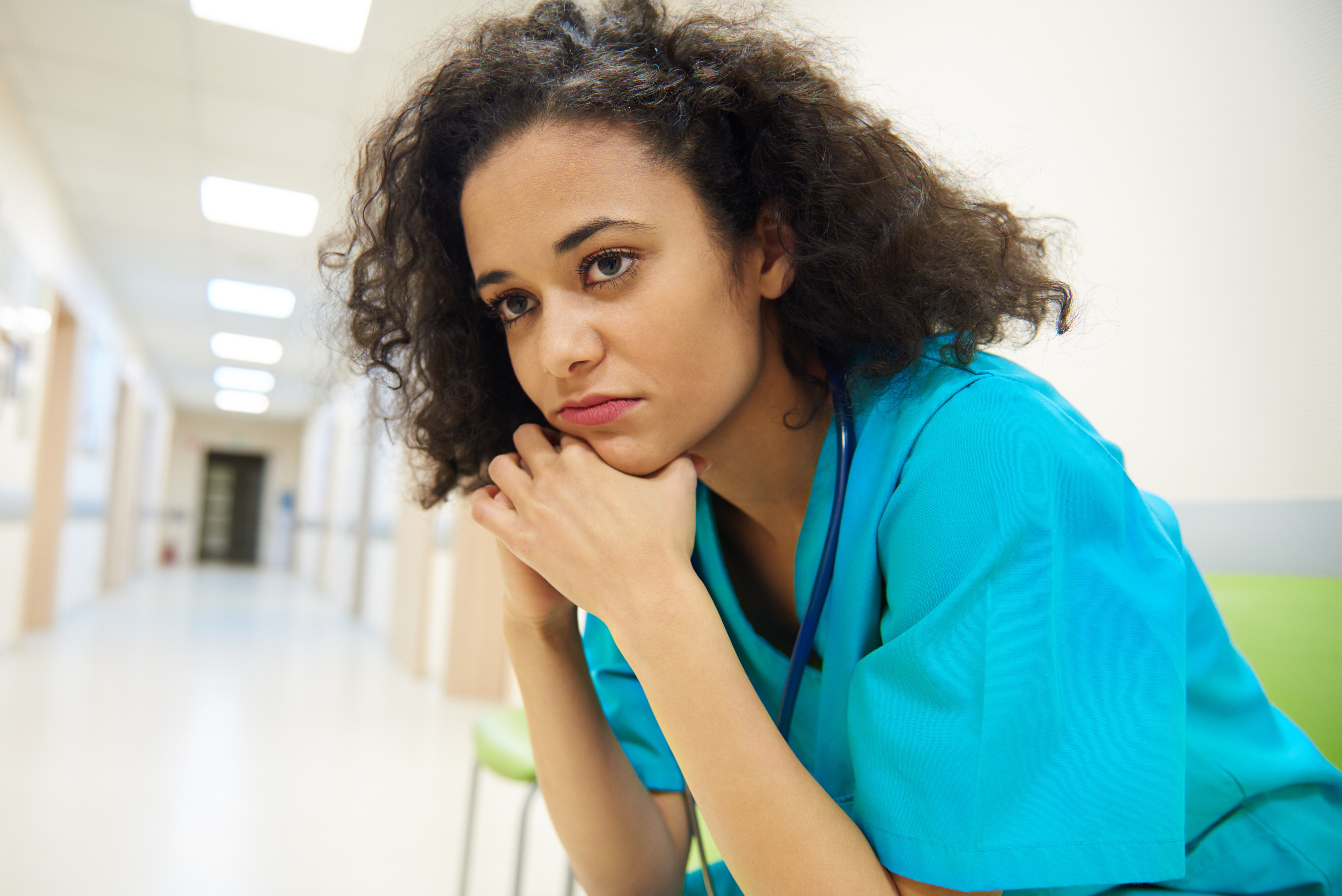 Clinician sits in hallway, frustrated with workflows and experiencing burnout