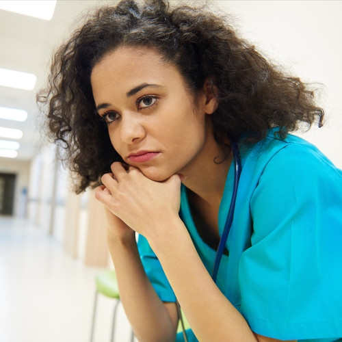 Clinician sits in hallway, frustrated with workflows and experiencing burnout