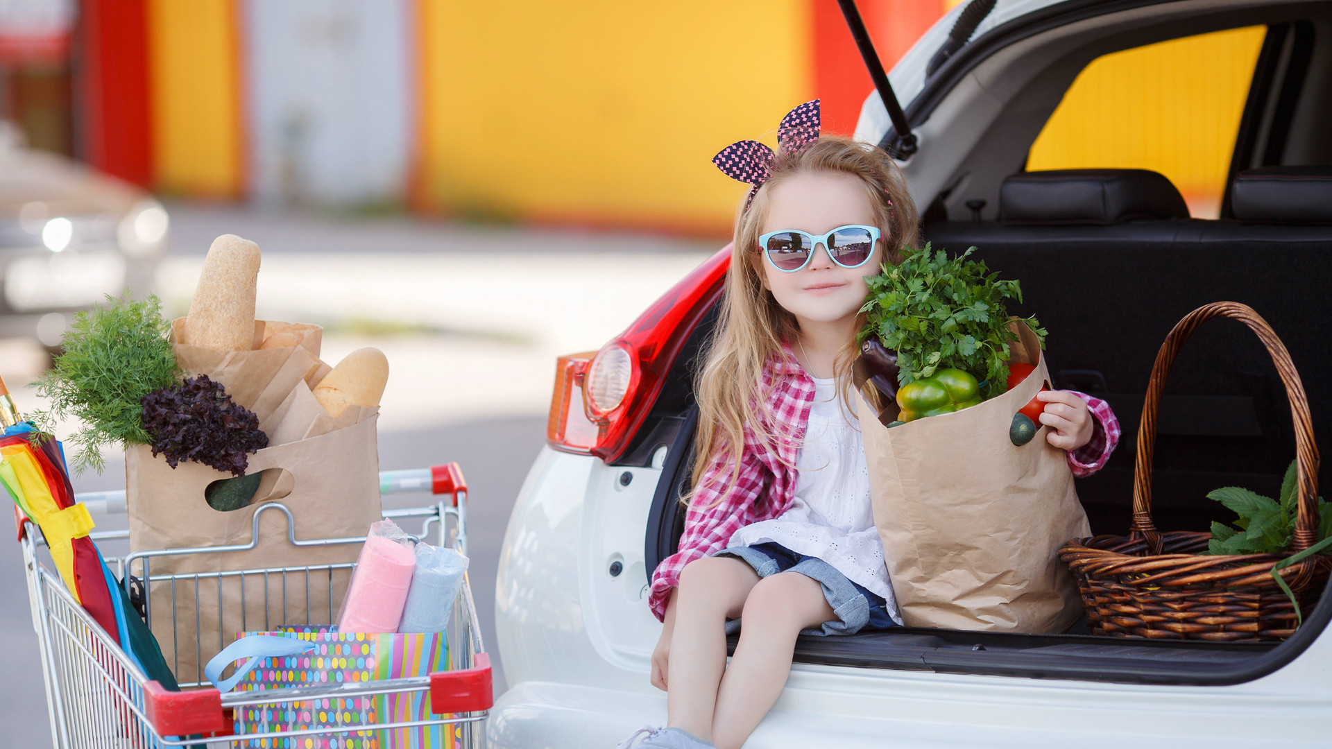 Little girl-the buyer of products, sitting in the open trunk of a car