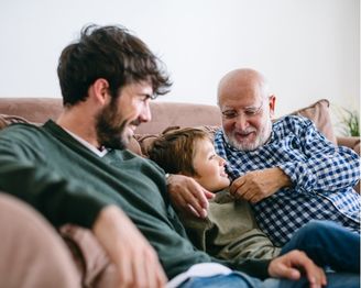 Dad receiving a wrapped Father’s Day gift from a child while sharing a meal together.