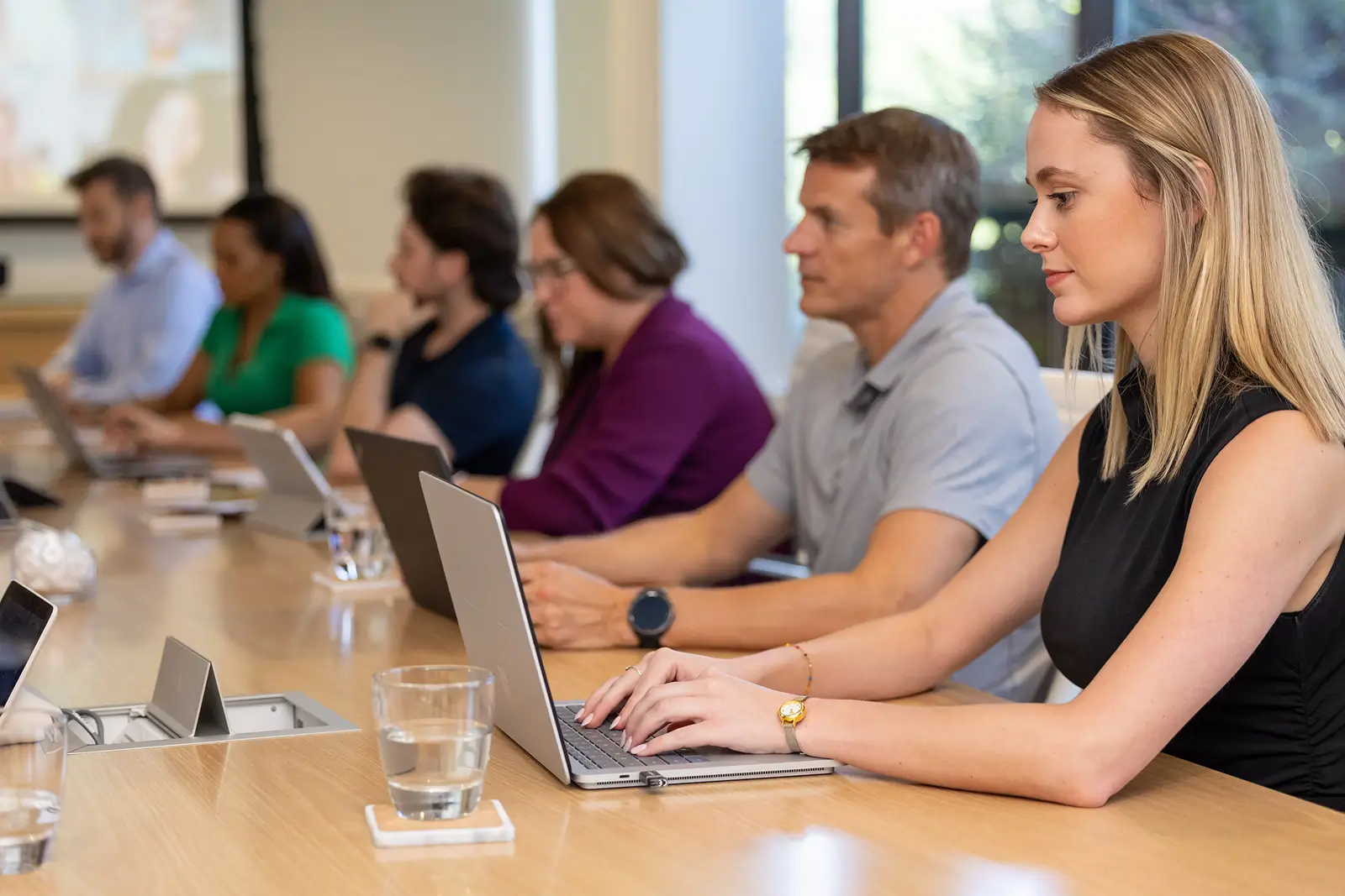Services professionals focused on their laptops at a shared desk in a collaborative work environment 