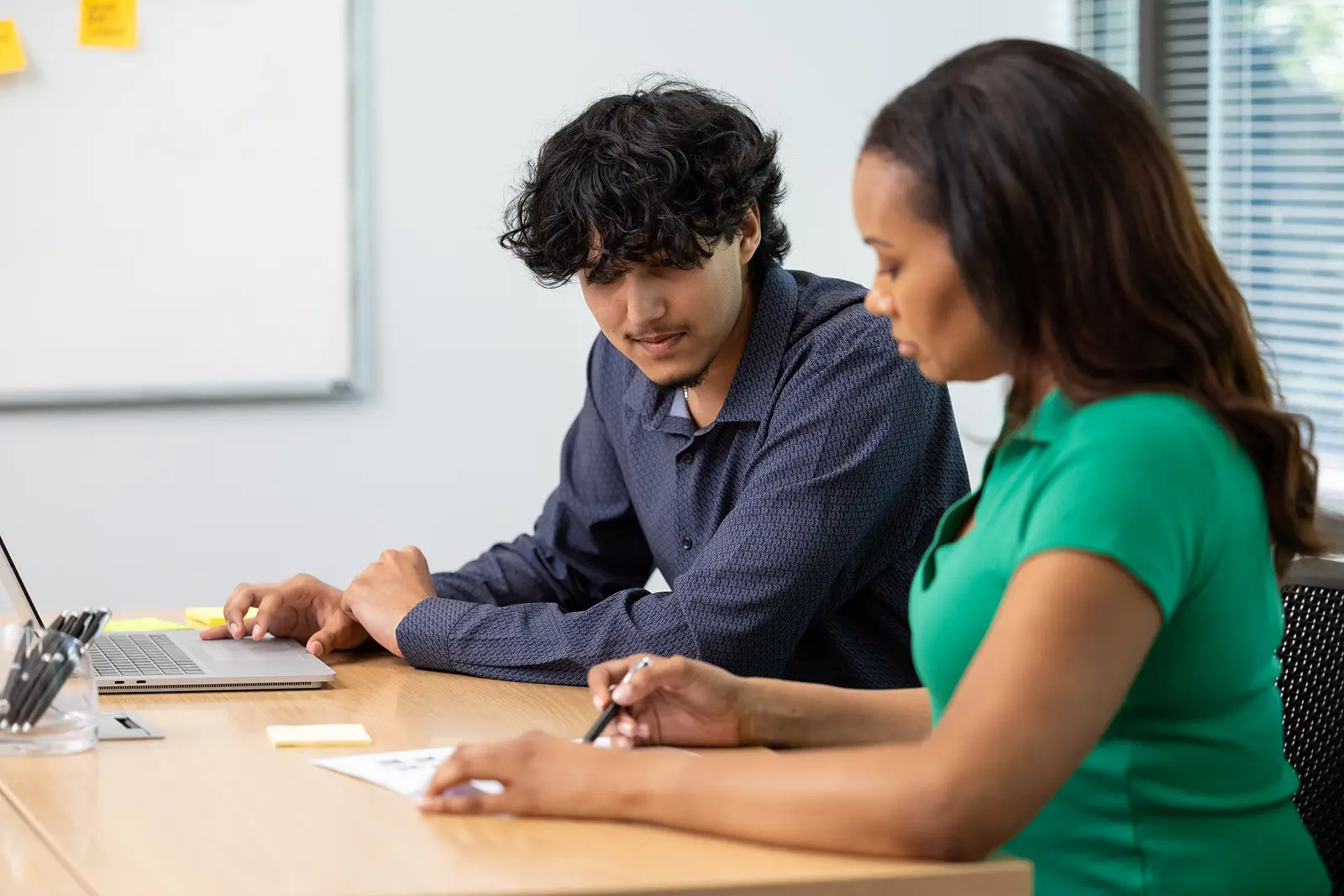 Services delivery team members discussing resource allocation for upcoming projects at a shared desk