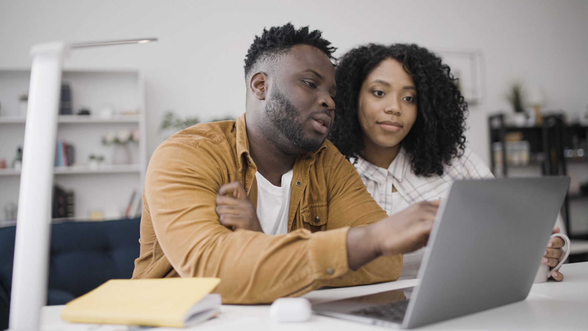 Young black couple discusses options as they choose a school for their child online