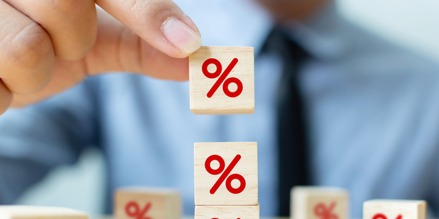 Interest rate financial and mortgage rates concept. Hand putting wood cube block increasing on top with icon percentage symbol upward direction