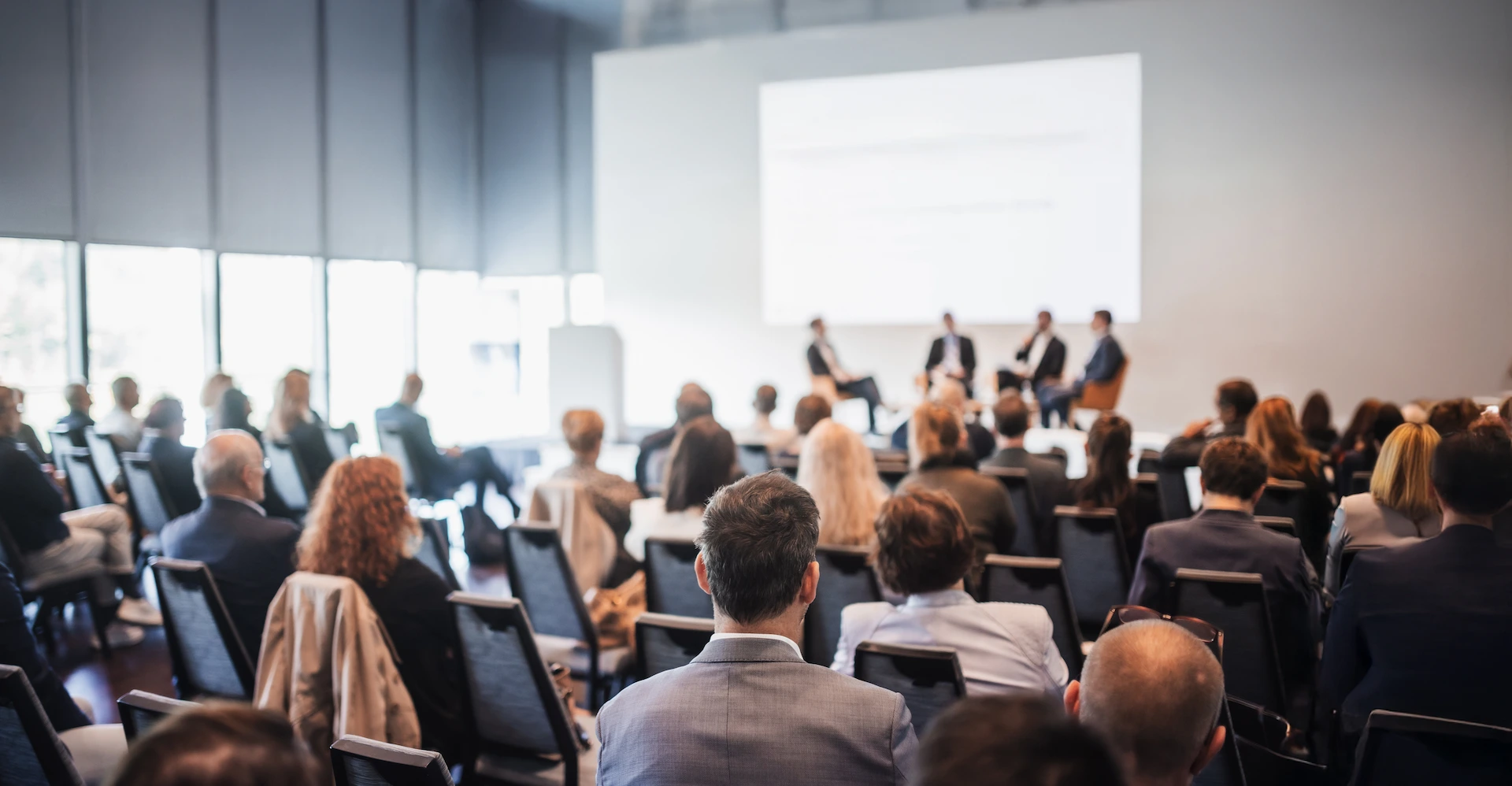 Audience watching four experts discuss a presentation in a conference hall.