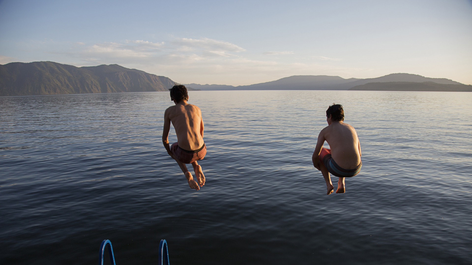 Boys jumping into lake from dock