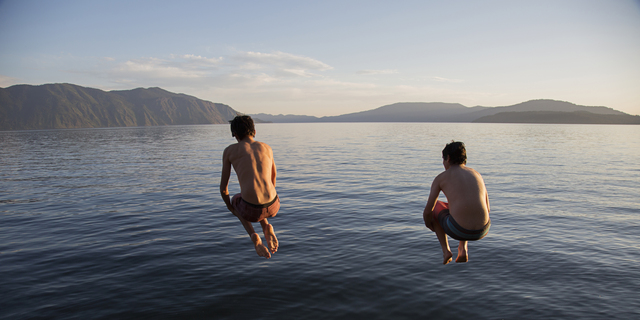 Boys jumping into lake from dock