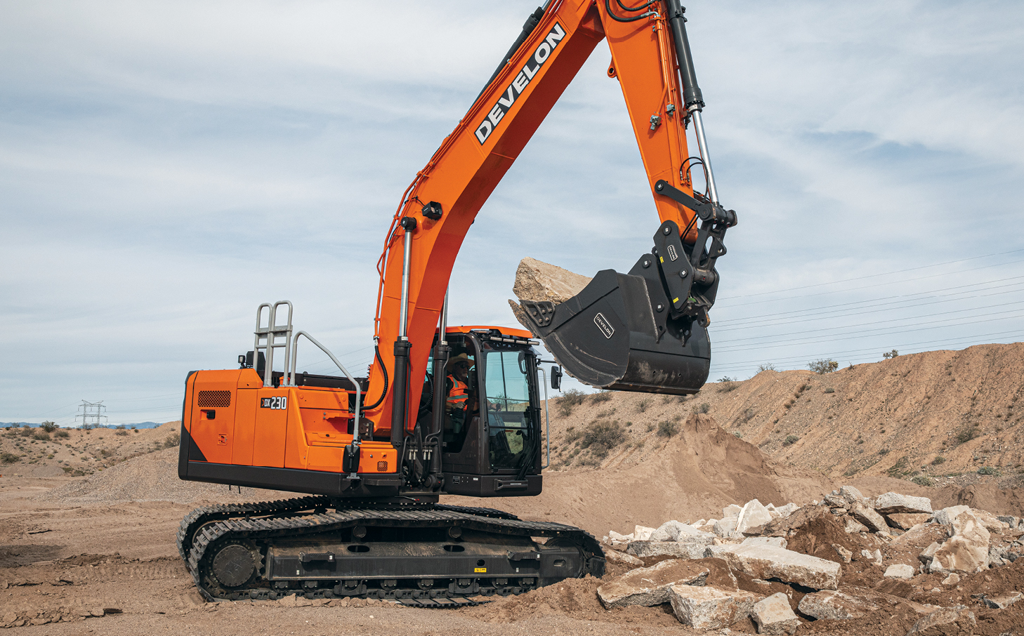 A DEVELON DX230LC-9 crawler excavator moving large pieces of concrete on a jobsite