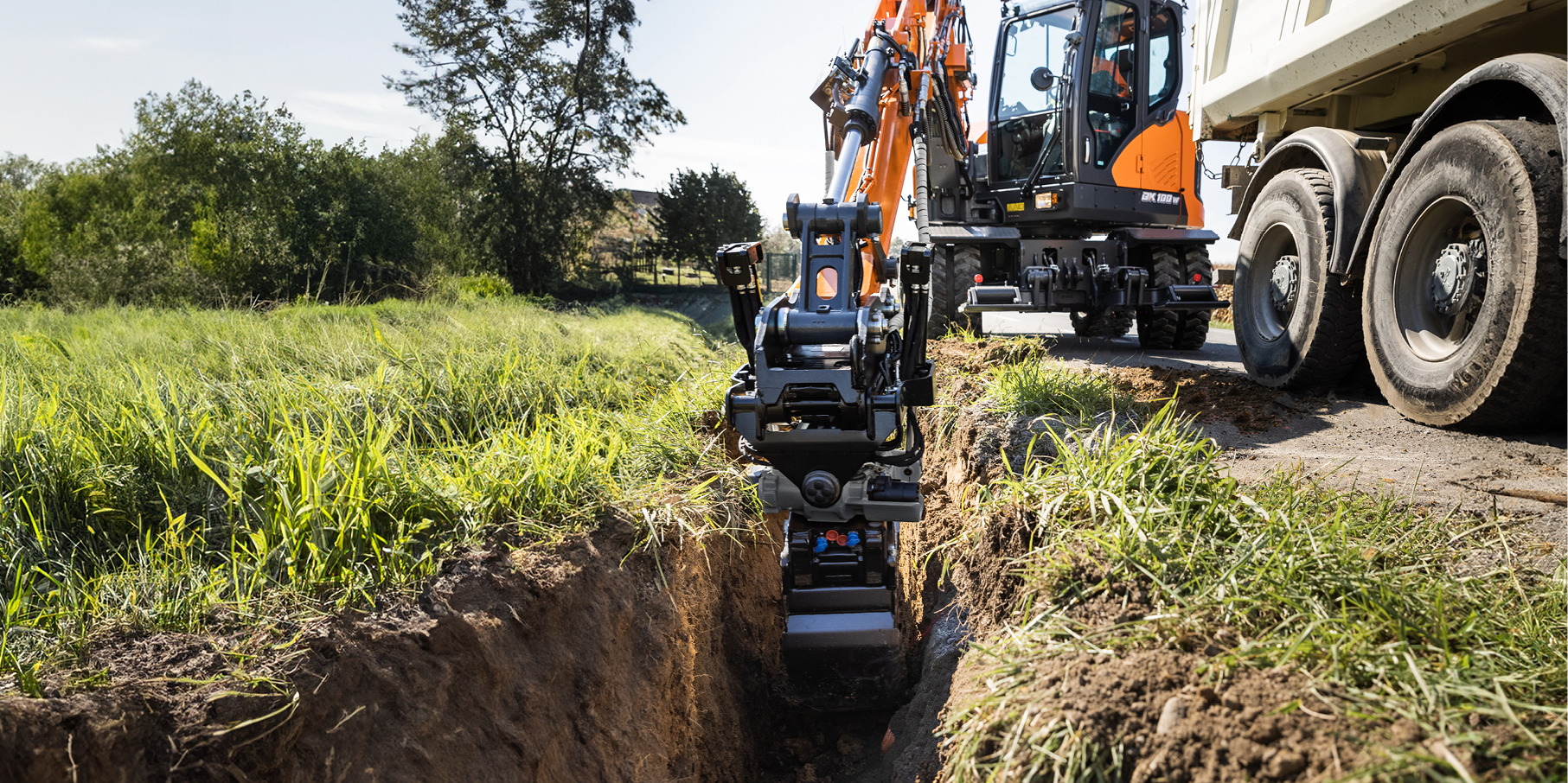 A DEVELON wheel excavator scoops dirt at a job site.