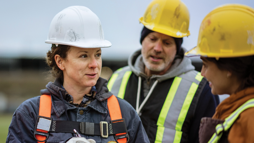 Three crew members talking on a job site.