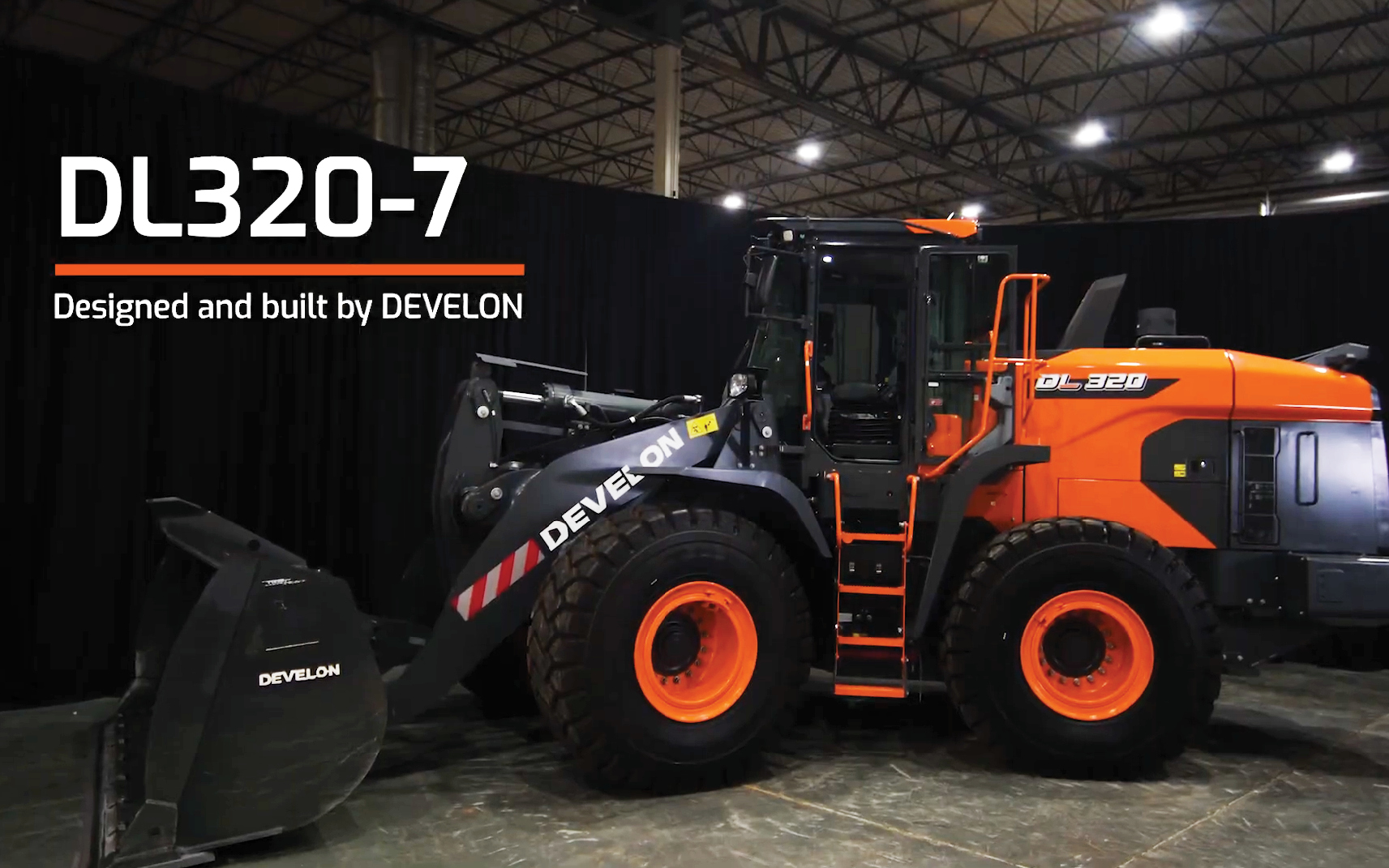 A DEVELON DL320-7 Wheel Loader sitting stationary inside of garage.